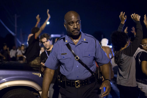 Capt. Ron Johnson of the Missouri State Highway Patrol walks through a crowd of demonstrators along West Florissant Avenue in Ferguson, Mo.